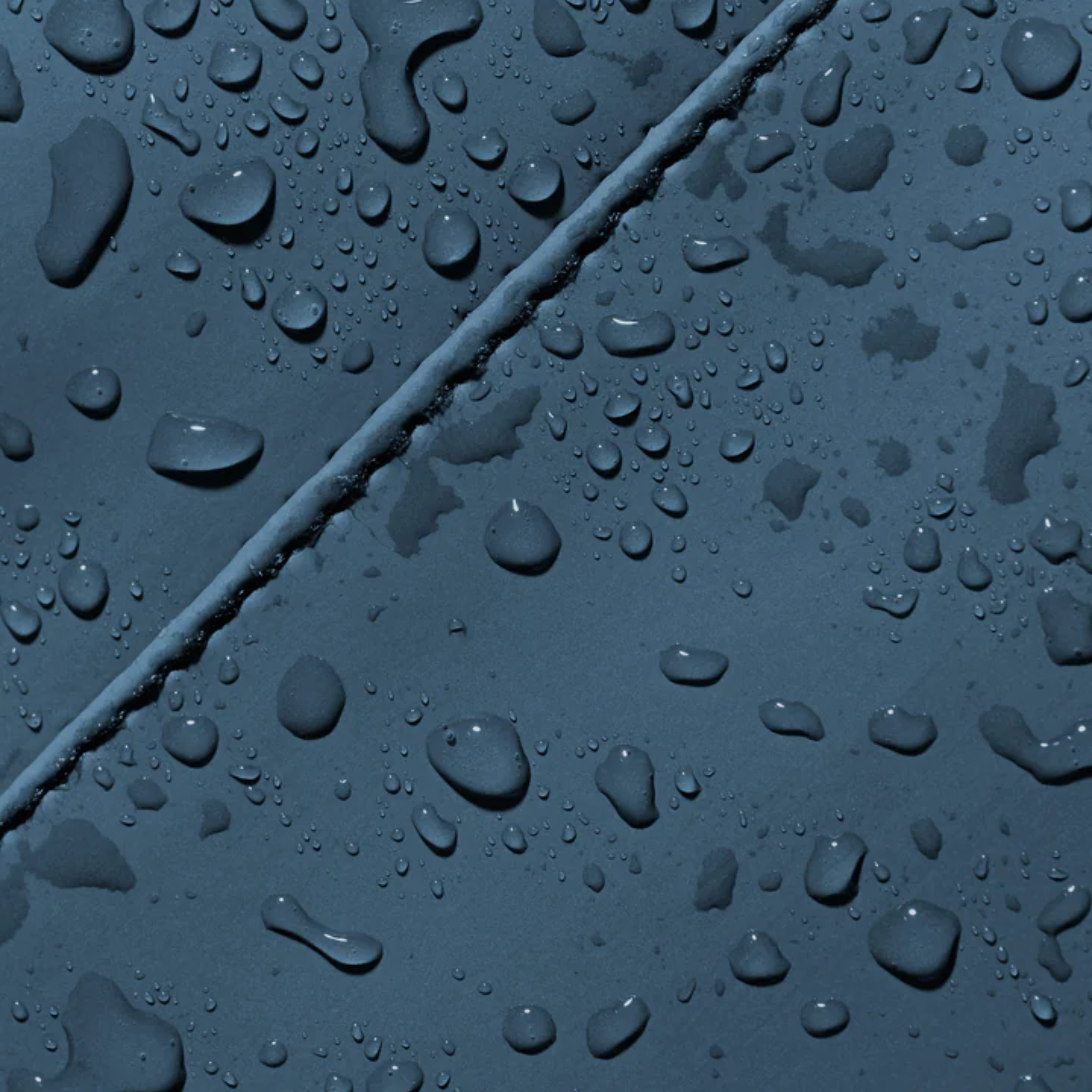Detail_waterafstotende_PU_stof_FRENKY_Bum_Bag_blauw_close-up_met_druppels.png