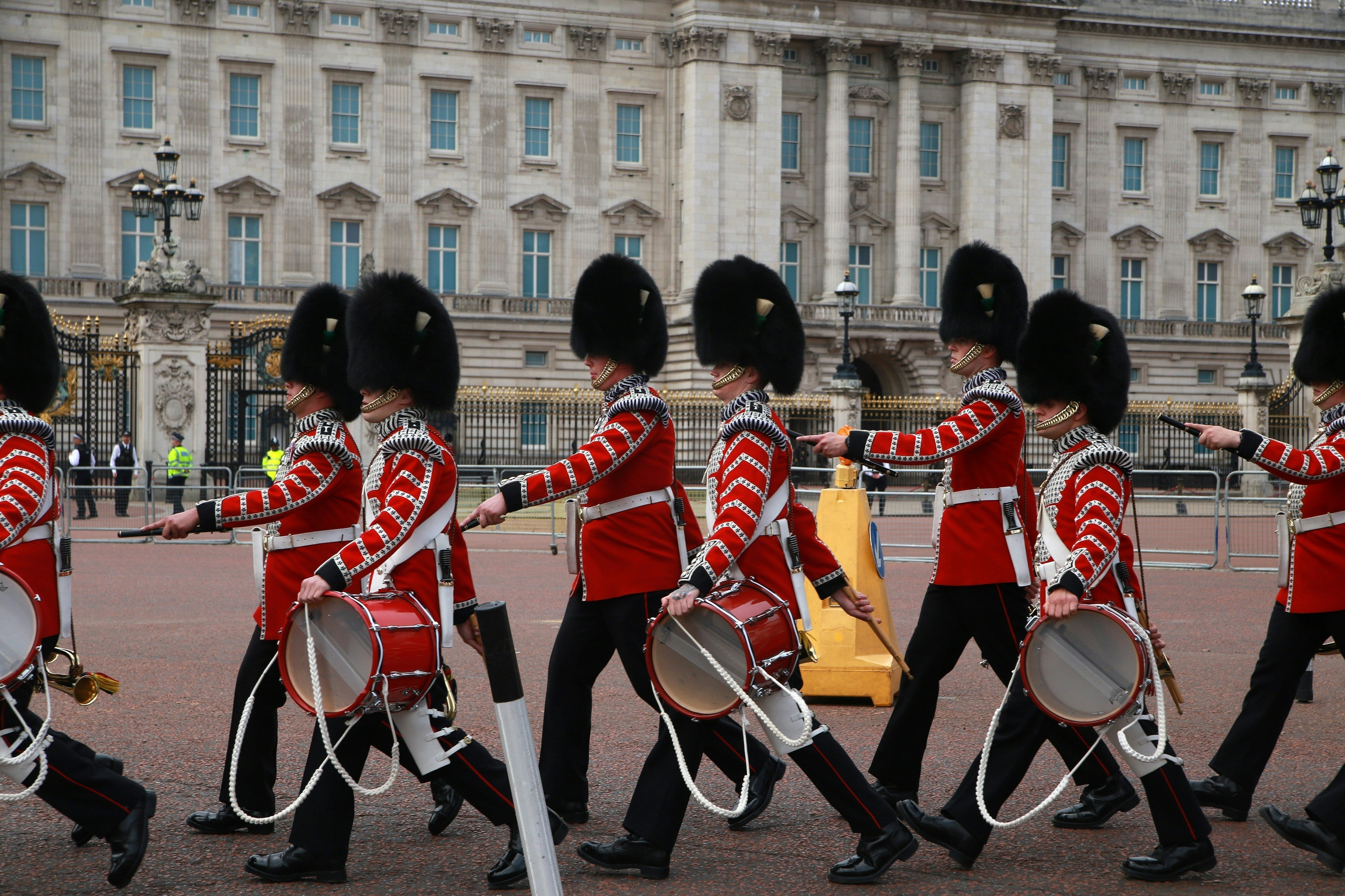  Beefeaters in red uniforms walking outside the Tower of London, London skyline in background