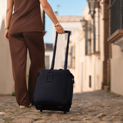 FRENKY zwarte handbagage koffer op wieltjes die over kasseien rolt in een Spaans straatje.