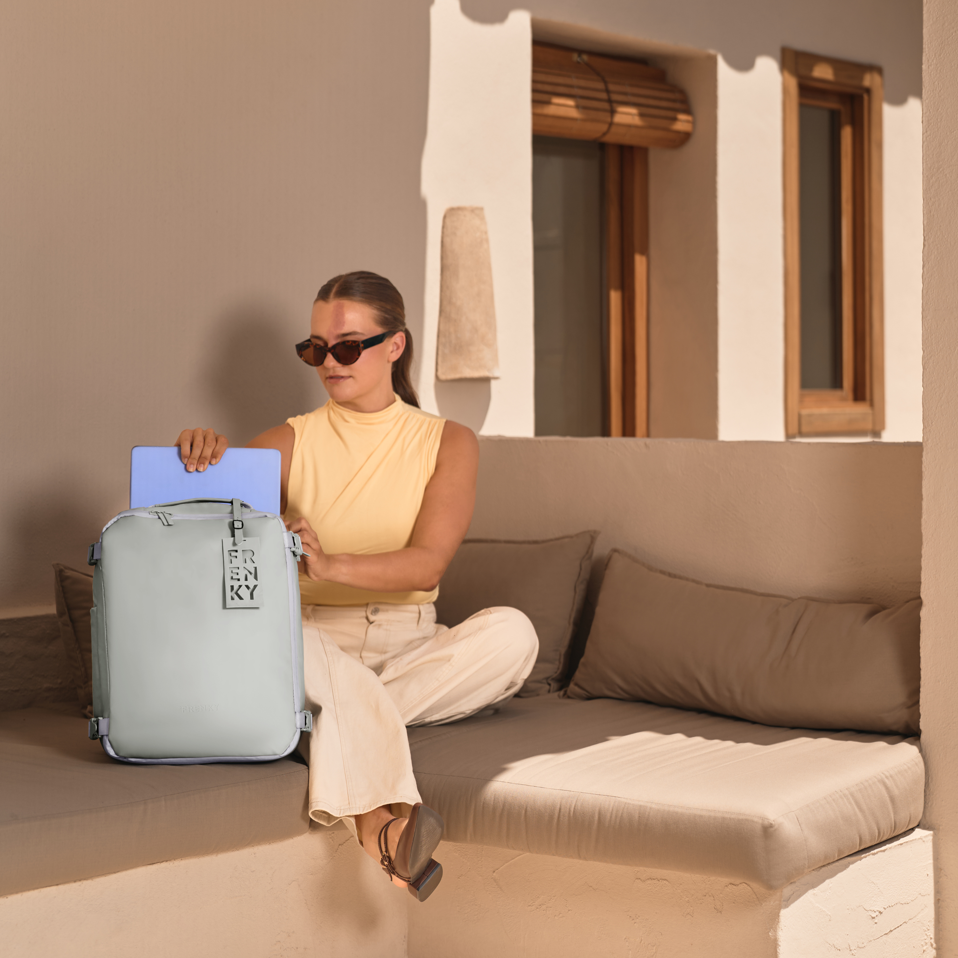 Model schuift een laptop in het speciale laptopvak van de lichte FRENKY underseat reisrugzak